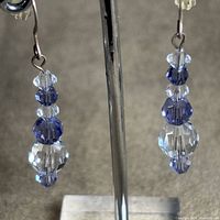 Close-up of both earrings hanging, showing crystal arrangement and metal hooks