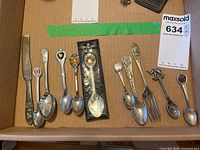 Overall view of all 12 silver-plated souvenir utensils laid out