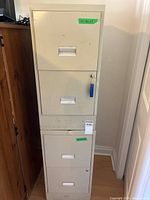 Both beige metal filing cabinets stacked showing four recessed handles and blue key fob