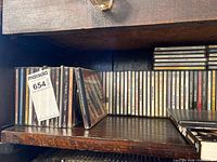 Shelf with long row of CD spines and leaning stack