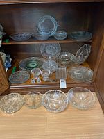 Shelf with multiple pressed glass bowls, plates, trays, lidded dish, shakers, open salts