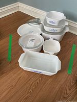 Group of CorningWare dishes and lids on floor