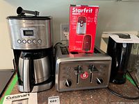All four appliances grouped: coffee maker, toaster, boxed can opener on top, kettle to right