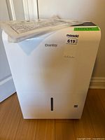 Front view of white Danby dehumidifier with instruction manual on top