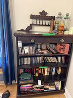 Full view of the bookcase loaded with books and CDs showing overall form, shelves, drawer, and backboard