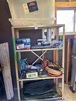Full view of shelving unit with tote on top, tools and cords on shelves