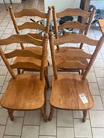 Front view of four matching wooden ladder-back dining chairs