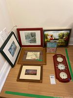 Group shot of six framed artworks and weather station