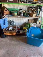 Full shelf view with birdhouse, pots, chemicals, tools, blue tote