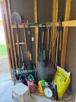 Overview of long-handle tools, watering cans, wire mesh, bags, stool and clock