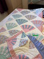 Quilt spread on bed showing overall fan block design and border