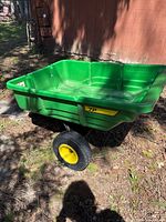 Side view of green John Deere 7P utility trailer with yellow wheels