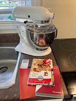 White KitchenAid stand mixer with stainless bowl and manuals on counter
