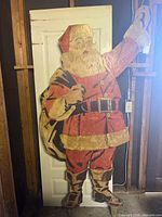 Front view of full wooden Santa figure leaning against door