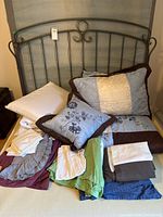 Headboard with piled pillows, throw, bed skirts, linens