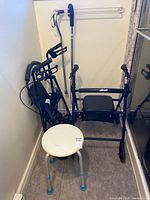 Two folded Drive rollators, cane, bath stool in corner
