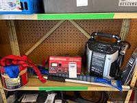 Shelf view showing all items: charger, booster pack, straps, handle tool