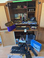 Overview of open wood cabinet showing routers, bulletin boards, keyboards, headphones, Linksys box