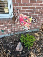 Full view of bell frame, garden flag, hummingbird stake and rock swan in garden bed