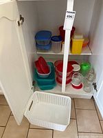 Cabinet showing all items including basket on floor, shelves with various plastic containers and glass jars
