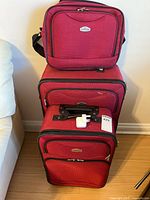 All three Cambridge red luggage pieces stacked with Apple adapter visible