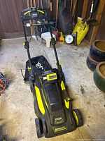 Full view of Ryobi mower with handle, wheels and grass bag attached