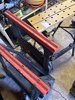 Two black plastic sawhorses with red clamp rails and folding workbench visible