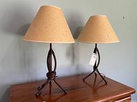 Two bronze-finish metal table lamps with paper shades on wood surface