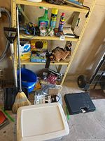 Wide view of metal shelf loaded with tools, cleaners, broom, shovel and containers