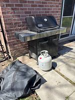 Weber Spirit grill with propane tank and cover visible
