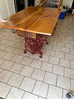 Full view of table showing plank top and red treadle base
