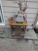 Overall view of wooden table, wicker basket on top, assorted metal stakes in front