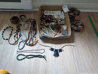 Lot overview in box and necklaces laid out on floor