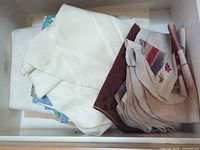 Stack of white linens and earth-tone napkins in drawer