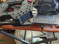 Overall view of Ridgid tile saw on metal stand with water tray and blade guard visible