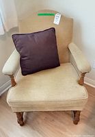 Front view of beige woven armchair with brown throw pillow