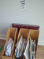 Front view of three plywood holders filled with papers, maroon photo album behind