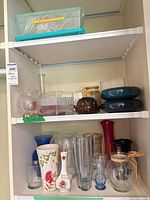 Shelf view showing multiple glass, ceramic and metal vases and containers
