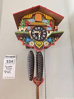 Full view of chalet cuckoo clock with weights and pendulum attached