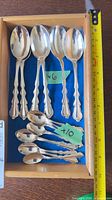 Wooden box with six larger dessert spoons and ten smaller teaspoons, measuring tape showing length
