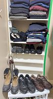Full shelving unit with folded sweaters, scarves, gloves, multiple pairs shoes and walking sticks