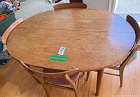 Top view of oval dining table showing wood grain, leaves in place, and portions of matching chairs