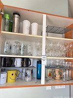 Cabinet showing full assortment: tumblers, plastic cups, pint glasses, wine glasses, mugs, steins