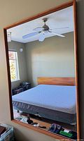 Full view of rectangular wood framed mirror hanging on wall