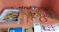 Overview of entire lot on shelf showing bangles in box, rings, chains, watch