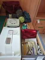 Overview showing yarn skeins, knitting needles, yarn winder, tool kit, measuring tape, pouch