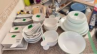 Countertop view of entire dinnerware lot showing plates, bowls, spoons and dishes