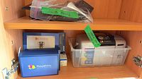Shelf showing printer in clear bin, PictureMate boxes, zip bag