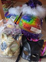 Overview showing both rainbow slipper boots, Venetian mask in bag, black cat mask