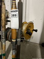 Cluster of fishing rods with reels attached, visible wood handles and yellow conventional reel